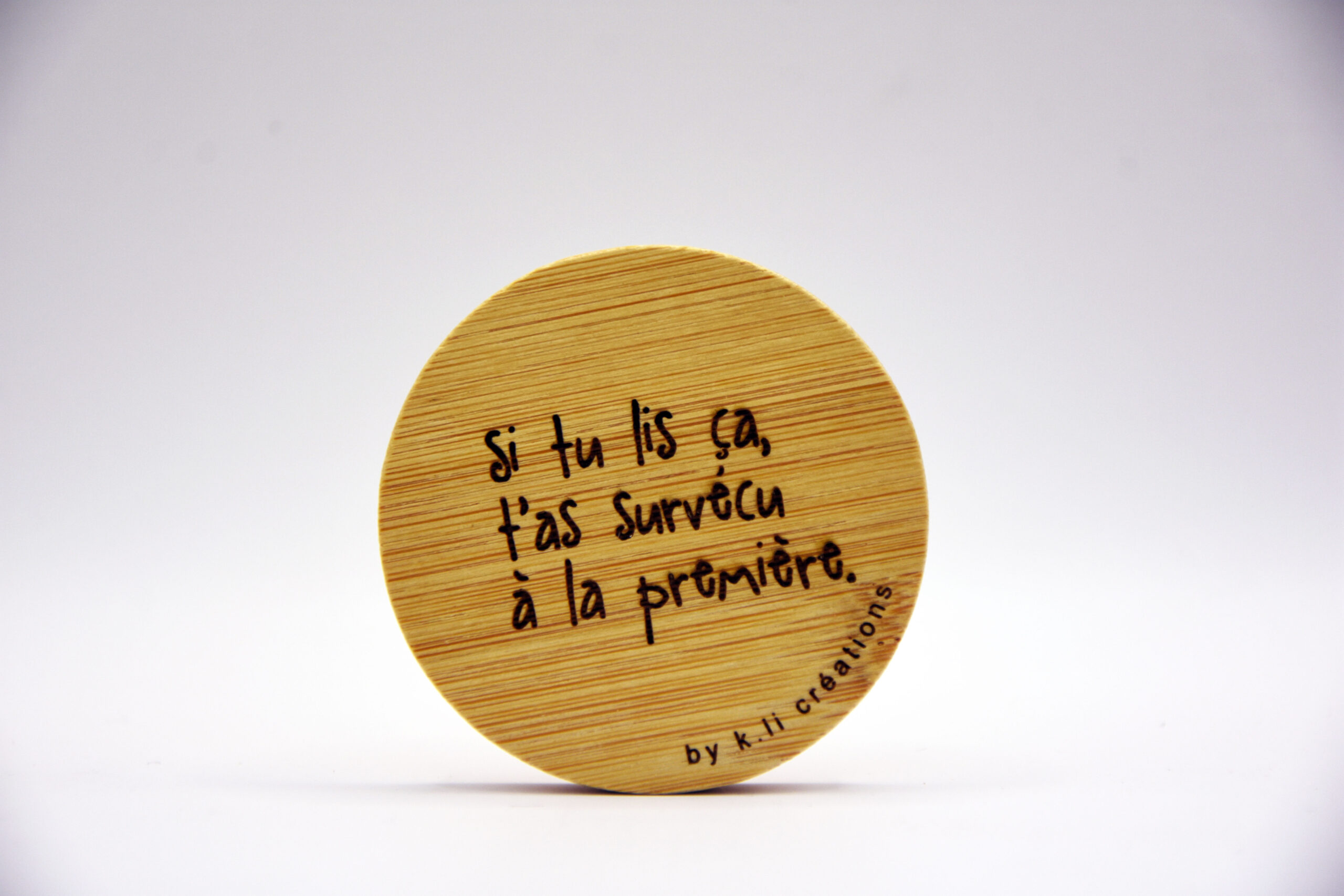 Décapsuleur rond en bois K.li Créations avec phrase humoristique “Si tu lis ça, t’as survécu à la première”.
